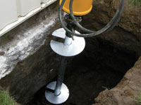 Installing a helical pier system in the earth around a foundation in Beckley
