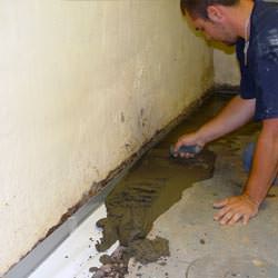 A basement waterproofer installing a perimeter drain system in Elkview