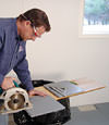 installing a waterproof vapor barrier on a basement floor to prepare for basement carpeting in a Beckley home